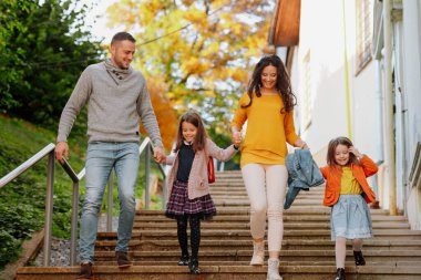 Kız kardeşler ve ebeveynler sıcak bir sonbahar gününde parkın merdivenlerinden aşağı iniyorlar. Hindistan yaz konsepti.