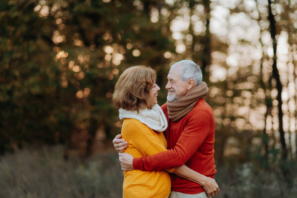 Romantic moment between senior couple, standing in the middle of autumn nature.