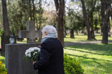 Yaşlı kadın mezarın başında duruyor, sevdiği birini hatırlıyor..