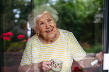 Bir fincan çayla yaşlı bir kadının portresi. Pencereden bakıyorum..