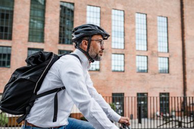 İşe bisikletle, işe giderken, sırt çantası ve kaskla..