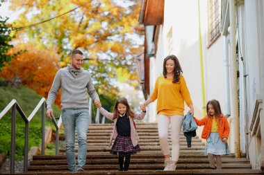 Kız kardeşler ve ebeveynler sıcak sonbahar gününde parkta yürürler. Hindistan yaz konsepti.