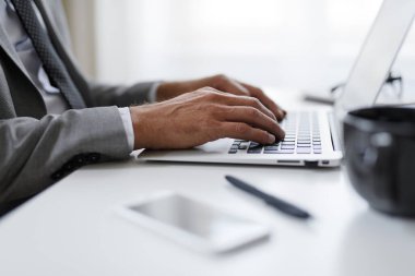 Ofiste dizüstü bilgisayarla çalışan iş adamlarına yakın çekim. Detaylar ellerde..