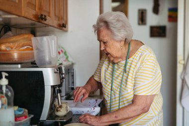 Kahve makinesinde kahve yapan yaşlı kadın. Yavaş sabah.