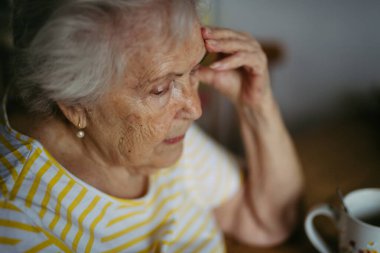 Mutfakta ağlayan, yüzünü kapatan endişeli yaşlı kadının portresi..