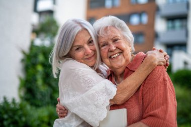 Güzel yetişkin bir kızın portresi ve yaşlı bir anne, birbirlerine sarılıyorlar..