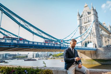 Olgun iş adamı akıllı telefona bakıyor, birini bekliyor..