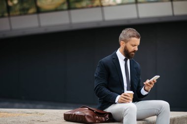 Olgun iş adamı akıllı telefona bakıyor, birini bekliyor..