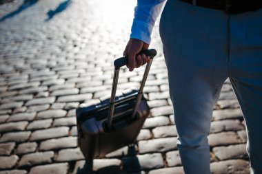 İş adamı şehirdeki kaldırım taşı caddesinde bavul taşıyor..