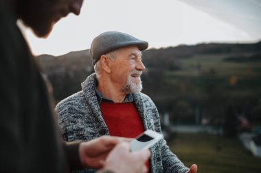 Adam yaşlılara akıllı telefondan bir şey gösteriyor. Dijital okuryazarlık.