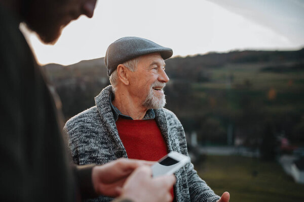 Man showing older person something in smartphone. Digital literacy.