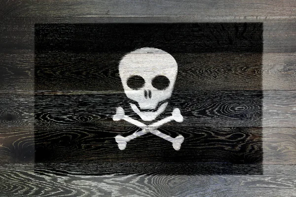 A Jolly Roger skull and cross bones pirate flag on rustic old wood surface background