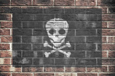 Eski tuğla duvar arka planında bir Jolly Roger korsan kafatası ve çapraz kemikli bayrak