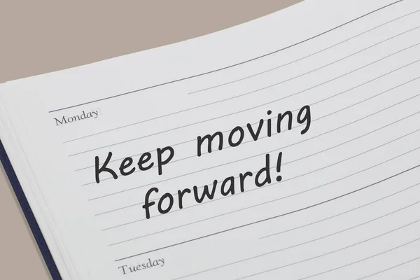 A Keep moving forward diary reminder appointment open on desk