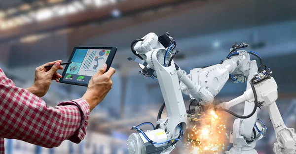 Industrial robot operator in factory holding tablet