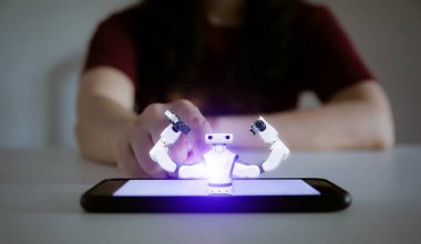 Yapay zeka robotu teknolojisi kavramı. İnsan eli akıllı telefona dokunuyor.