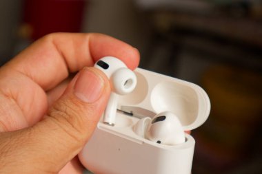 Beyaz hava podlarının yakın plan bir resmi, bir elde sallanıyor, stil ve rahatlığın simgesi..