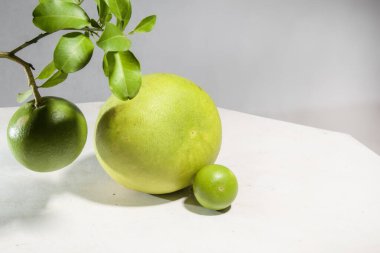 Beyaz arka planda taze yaprak saplı Pomelo meyvesi