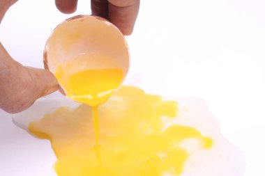 Adamın eli, beyaz arka planda yumurtanın yarısını açık tutuyor. Bir yumurta kırıldı. Kırpma yolu ile. en üstteki görünüm