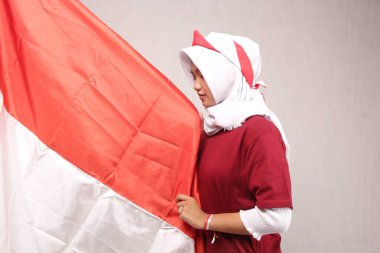 Beyaz arka planda Endonezya bayrağına bakarken kırmızı ve beyaz bayrağı öpen Asyalı bir kadının portresi