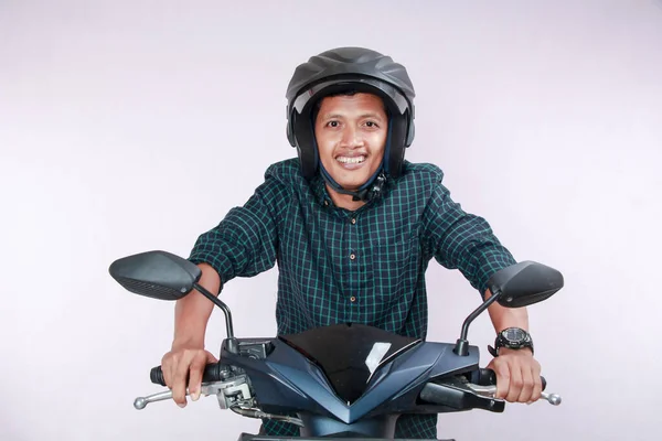 Tanned Asian mature man in green checkered suit showing excited expression while riding motorbike, isolated on white.