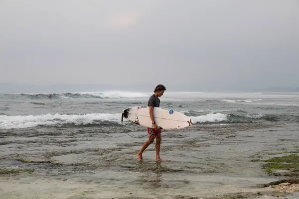 Tanjung Setia Krui, Lampung; 27 Mayıs 2024; Tanjung Setia sahilinin batı kıyısında sörf tahtaları taşıyan sörfçüler
