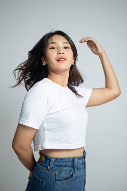 Güzel Asyalı yüzün portresi. Saçları şehvetli bir yüzle uçuyor. Dar beyaz tişörtlü bir kadın. beyaz arkaplanda izole,