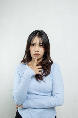 Eli çenesinde kasvetli ve duygusal bir görünüm içinde, mavi bir bluzu ve uzun saçları olan güzel bir kız, kadın elinin bir hareketiyle ayakta duruyor.