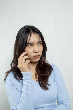 Güzel ve kızgın bir kızın portresi. Başka birini çağırmak için bekliyor. Açık mavi günlük kıyafetler giyiyor.