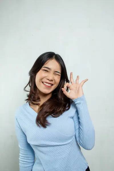 stock image cute hysterical woman standing with stylish three finger salute and light blue casual, young asian woman on isolated white background