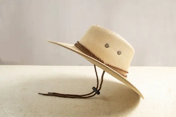 stock image texture closeup of flying cowboy hat side view with protected chin strap on table, men's wide brimmed straw hat