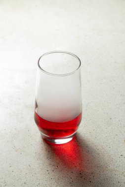 Bir bardak kırmızı sıvı ya da kırmızı bira granit desenli terrazzo fayans masasında yatar.