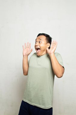 Asyalı bir adamın şaşırmış ve şaşırmış yüzü. Beyaz, yeşil tişörtlü..