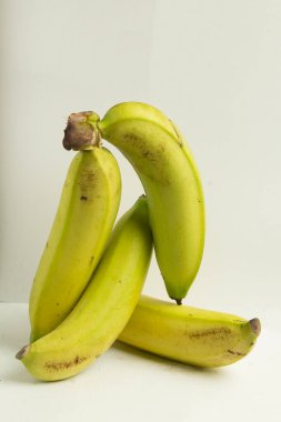 Beyaz üzerine izole edilmiş genç yeşil ya da genç sarı muz yığını.