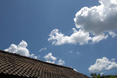 Çatıda kabarık bulutların olduğu güneşli bir gün.