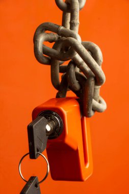 Çift disk kilit ve turuncu zemin üzerinde gümüş paslı demir zincir.