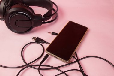 Kulaklıklar ve Akıllı Telefon Pembe Yüzeyde Bağlandı