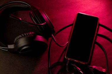 Kırmızı ışık altında akıllı telefon ve kulaklıkla oyun düzeneği