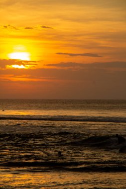 Gölgeli sörfçülerle okyanusun üzerinde gün batımı