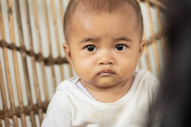 Bir bebeğin yemek yemeyi reddeden ve bakışlarıyla bir sandalyede oturan yüzünün yakın çekimi.