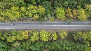 Autumn, Broken Bow, Oklahoma, ABD 'de yeşil ormandan geçen taşra yolunun yukarıdan görüntüsü. Drone görünümü