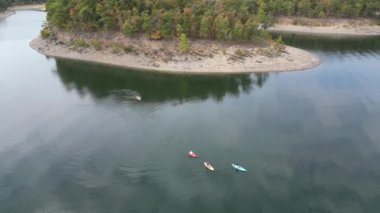 Broken Bow Gölü 'nün havadan görünüşü. Suda kanoları var, Oklahoma, ABD. Sahilde sonbahar manzarası ve kıyıda bir orman.