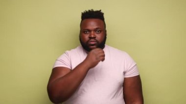 Kimseye anlatmam. Gözü korkan Afro-Amerikan bir adam pembe tişörtlü fermuarlı dudaklı ve kameraya bakıyor, ağzını kapatıp sır tutacağına söz veriyor. Açık yeşil arka planda kapalı stüdyo çekimleri