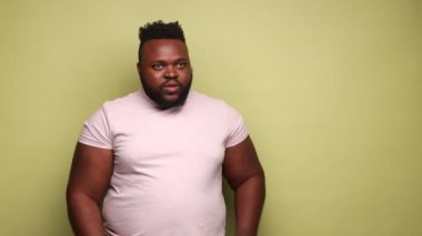 Ticari teklife bak. Afro-Amerikalı adam fotokopi alanını işaret ediyor ve hayretle bakıyor, sunum için boş yer gösteriyor. Açık yeşil arka planda kapalı stüdyo çekimleri.