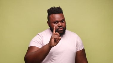 - Dikkatli ol. Söylemiştim sana. Afro-Amerikalı adam hata uyarısı yapıyor, kameraya uyarı parmağı ve endişe verici bir şekilde bakıyor, tavsiye veriyor. Açık yeşil arka planda kapalı stüdyo çekimleri.