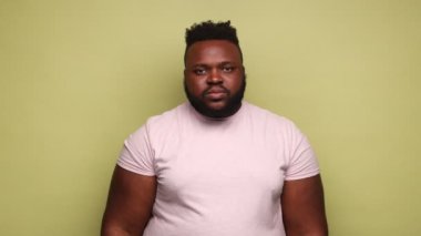 Sona geldik. Ciddi sakallı Afro-Amerikan bir adam pembe tişörtlü, ellerini çapraz yapıyor. X işareti, reddedilme. Açık yeşil arka planda kapalı stüdyo çekimleri.