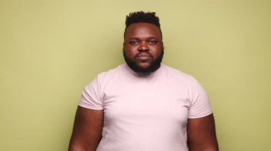 Ellerinde pembe tişört giyen gülümseyen Afro-Amerikan adam iki çok kültürlü kağıt insanı, çokuluslu ırk birliği kavramı. Açık yeşil arka planda kapalı stüdyo çekimleri.