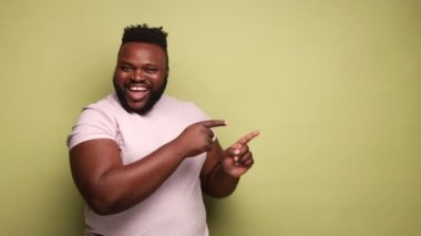 Bana bak. Pembe tişörtlü, solu işaret eden Afro-Amerikan bir adam. Mesaj için boş bir yer. Reklam. Açık yeşil arka planda kapalı stüdyo çekimleri.