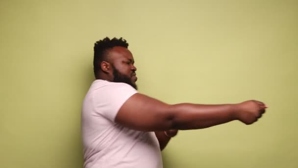 强壮而有目标的非裔美国人穿着粉色T恤 拉着无形的绳索 表现出了他的毅力和领导才能 室内拍摄被隔离在浅绿色背景下 — 图库视频影像