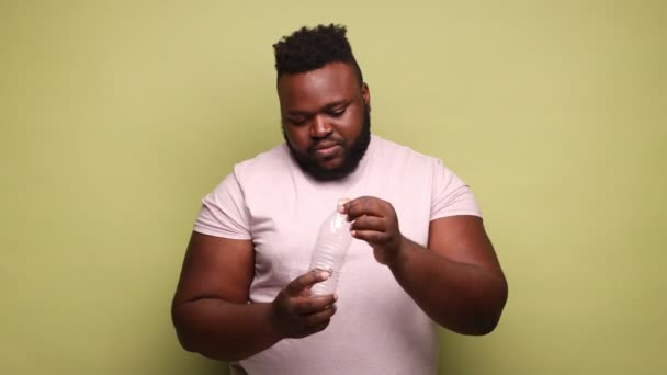 Hombre Afroamericano Con Camiseta Rosa Apretando Botella Plástico Mirando Cámara — Vídeos de Stock